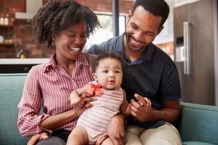 family-with-baby-daughter-relaxing-on-sofa