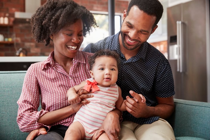 family-with-baby-daughter-relaxing-on-sofa
